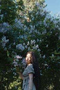 Portrait of woman standing against tree