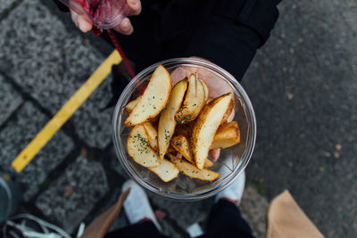 Cropped hand holding cooked potatoes in bowl