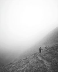 Rear view of man hiking on mountain during foggy weather