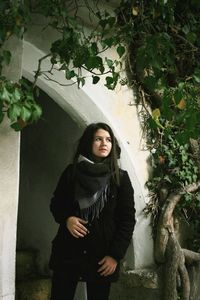 Portrait of a young woman standing against plants