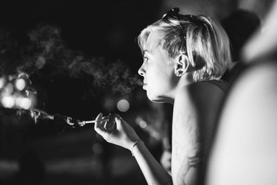 Woman smoking cigarette in city at night