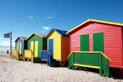 Colorful huts at sandy beach against sky