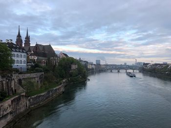 Buildings at waterfront against cloudy sky