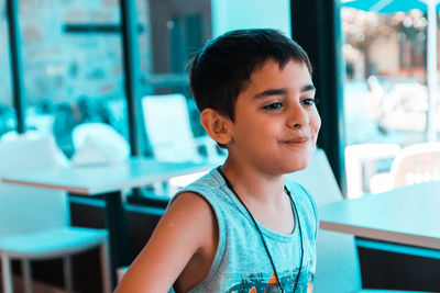 Smiling of boy looking away while sitting at table in restaurant
