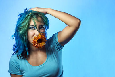 Portrait of beautiful woman standing against blue background