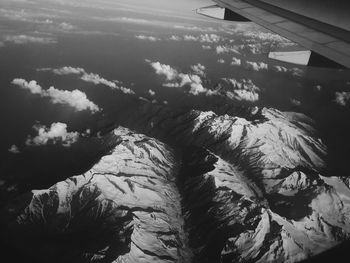 Aerial view of airplane wing over landscape against sky