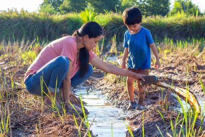 Mother and cute little boy playing in the mud puddle in the rice field.