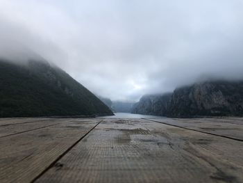 Surface level of footpath leading towards mountain against sky