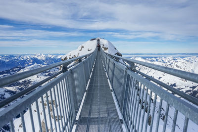 Bridge over snowcapped mountain against sky