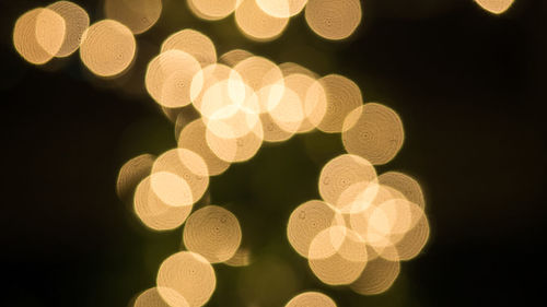 Defocused image of illuminated lights against black background