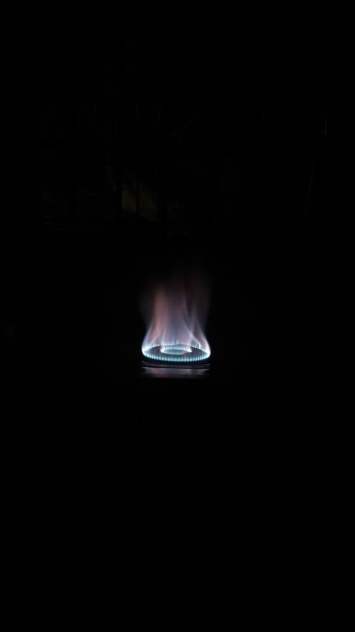 CLOSE-UP OF LIT CANDLE IN DARK