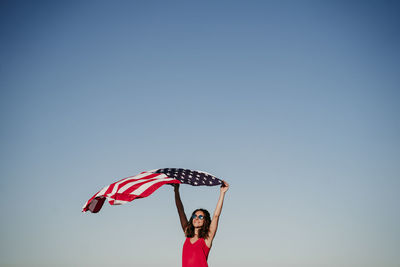 Low angle view of woman standing against clear blue sky