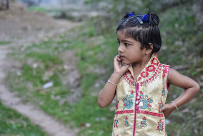 Girl looking away while standing outdoors