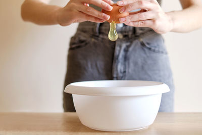 Woman breaks an egg with a knife over a plate to cook a delicious meal