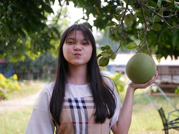 Portrait of young woman standing against trees