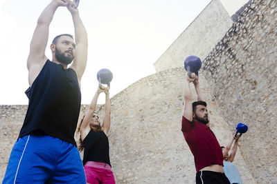 Athletes lifting a kettelbell crossfit weights in an urban enviroment.