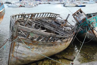 Wrecked boats moored at harbor