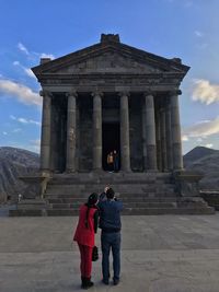 Rear view of tourists at historical temple against sky