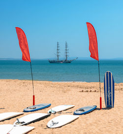 Sailboats moored on beach against blue sky