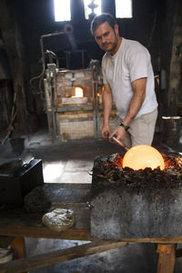 Man putting molten glass in a mold in a glass factory