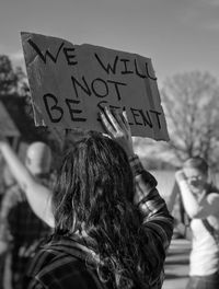 Rear view of female protestor protesting with placard in city