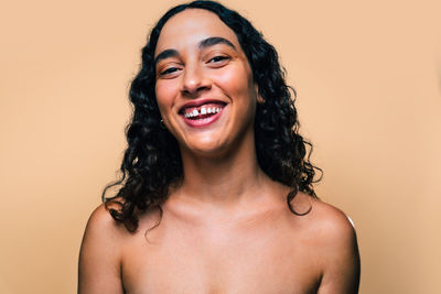 Portrait of young woman against yellow background