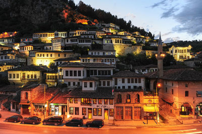 Illuminated building by street against sky at night