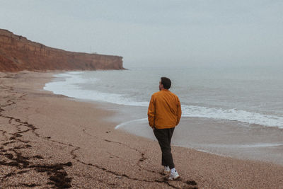 Rear view of woman walking at beach