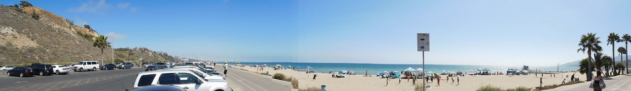 Panoramic view of people at beach against blue sky