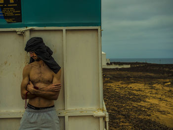 Rear view of shirtless man standing against sky