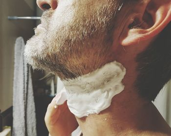 Midsection of man applying shaving foam in bathroom