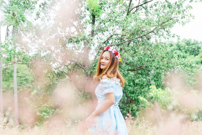 Portrait of smiling woman standing against trees