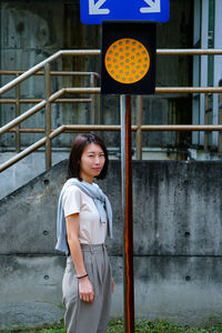 Smiling woman standing by traffic signal