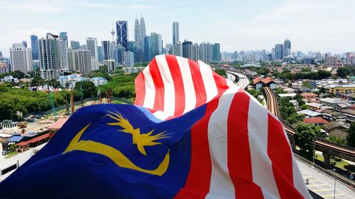 Close-up of malaysian flag against cityscape