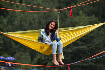 Full length of smiling woman sitting on hammock