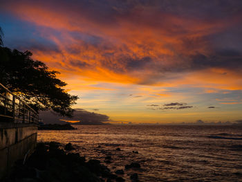 Scenic view of sea against dramatic sky during sunset