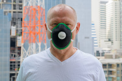 Close-up portrait of man wearing mask against city