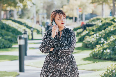 Young woman standing against trees