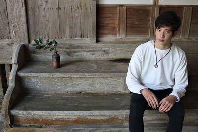 Side view of young man standing against wall