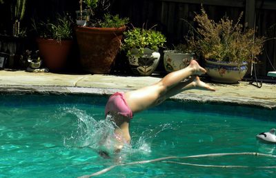 Girl in swimwear diving in turquoise swimming pool