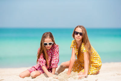 Young woman wearing sunglasses on beach against sky