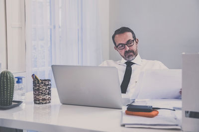 Business man works with laptop sitting at the desk. male at computer work online with remote office