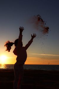 Silhouette woman standing by sea against sky during sunset