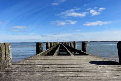 Wooden pier over sea against sky