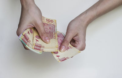 Close-up of hand holding paper over white background
