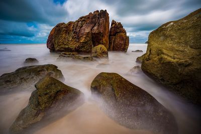 Scenic view of rocks in sea against sky