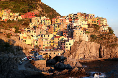 Buildings on mountain by sea against sky