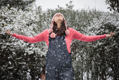 Happy young woman with arms outstretched in snow