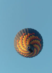 Low angle view of hot air balloon flying against clear blue sky