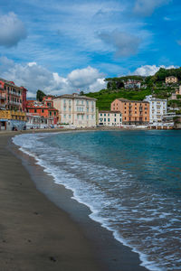 Buildings by sea against sky